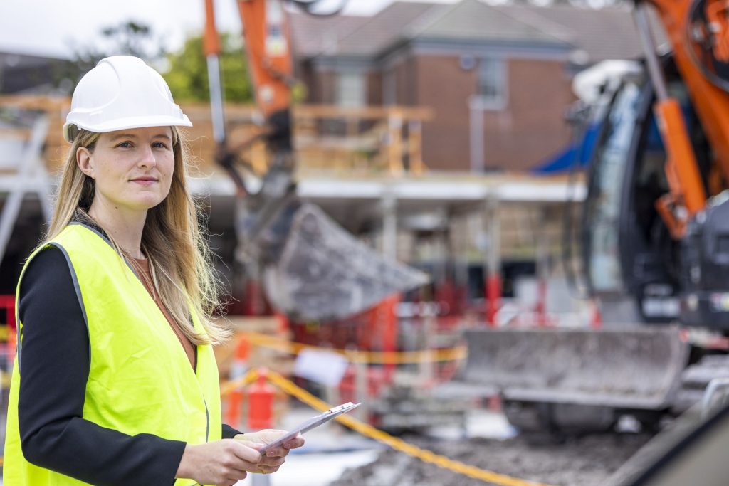 Woman in construction site holding a clipboard.
