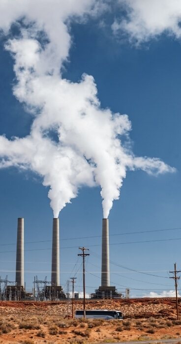 Gray concrete factory chimney releasing smokes